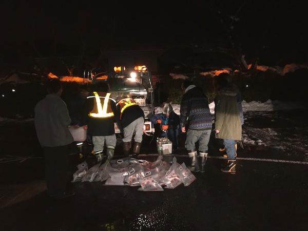 暗闇の中、給水車にライトを照らし水を取りに来ている住人の方に給水している写真